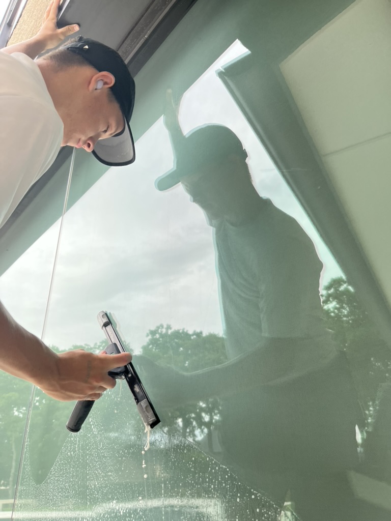 Close-up of a squeegee finishing a soapy window